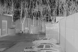 a thermal image of a person sneaking around a parking lot