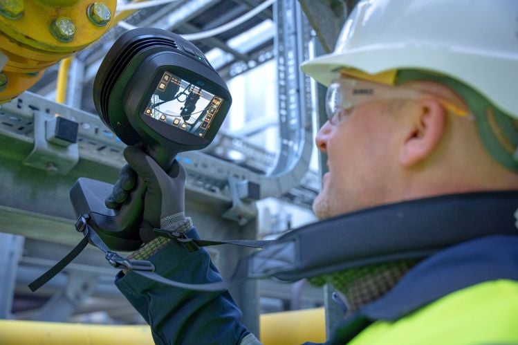a maintenance worker pointing a flir si2-ld at a piece of machinery and seeing an air leak